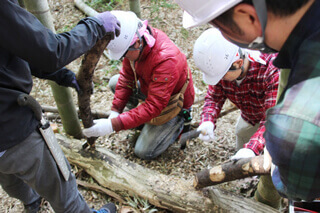 里山の道づくりでは里山にある資源をフル活用します。敷き竹を固定するのに欠かせない杭も、鉈（ナタ）を使って手作り。