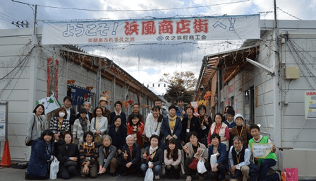 仮説住宅の商店街、「浜風商店街」で地酒や地元の食材を購入する参加者。購入することで応援の気持ちを伝えます