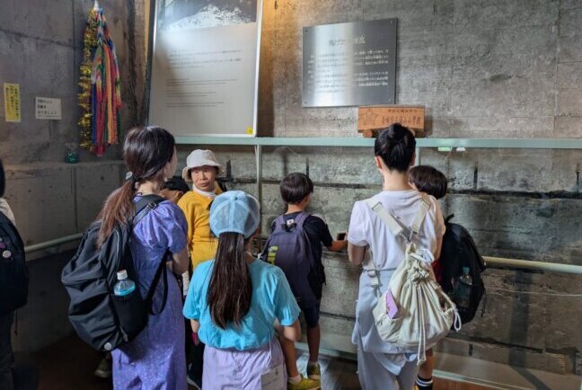 平和記念館の展示品について説明を聞く参加者